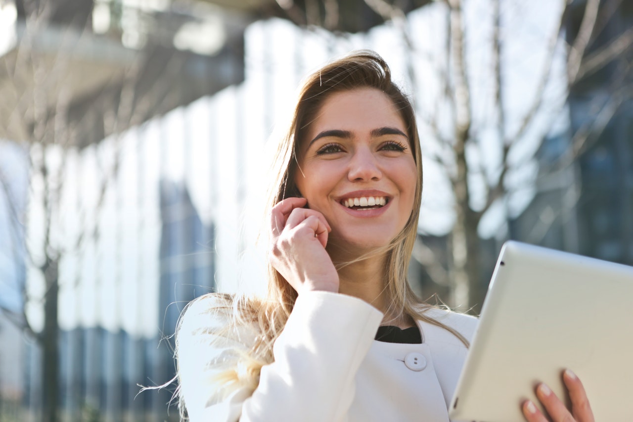 a woman smiling and holding a laptop