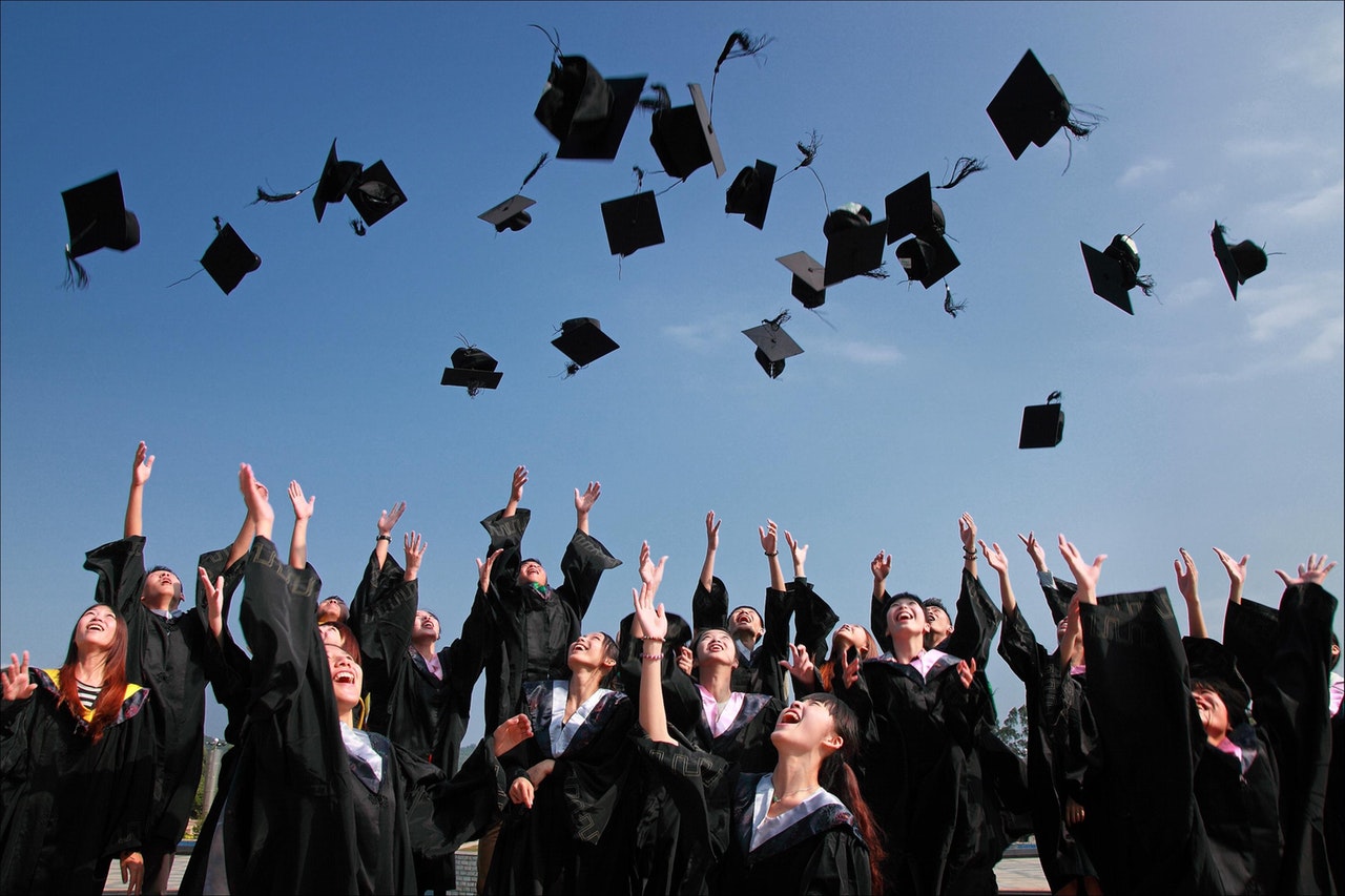 a group of people throwing their hats in the air