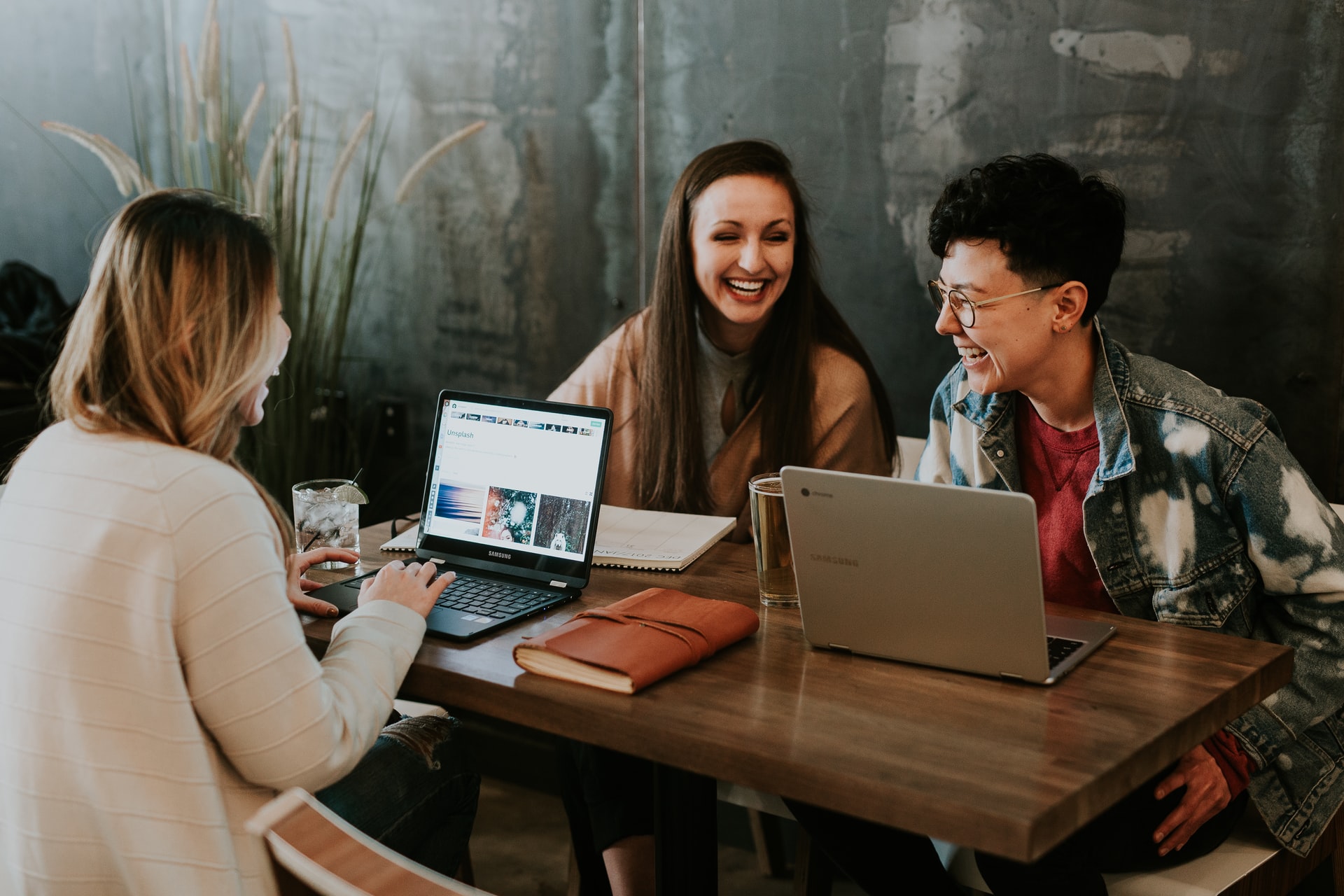 a group of people sitting at a table with laptops