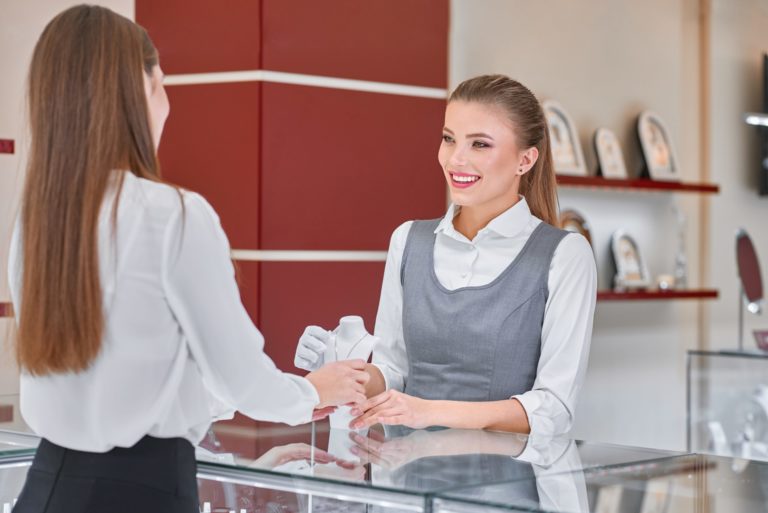 Young female jewelry worker helping to choose a necklace for a woman in a jewelry store